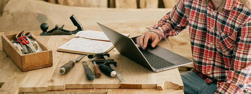 Contractors Insurance in Spokane, WA - Image of a person on their laptop with tool set up nearby